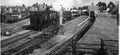 Vintage black and white photograph of a train station with trains and tracks.
