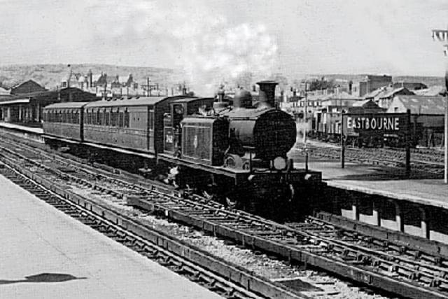 Vintage steam train on tracks with station buildings in the background