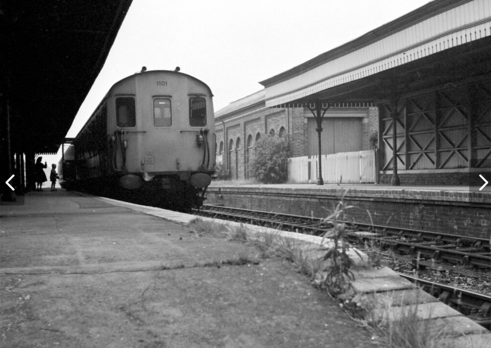 Vintage train at a station platform with a building in the background