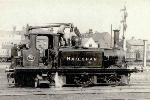 Vintage steam locomotive with 'Hailsham' branding on a railway track.