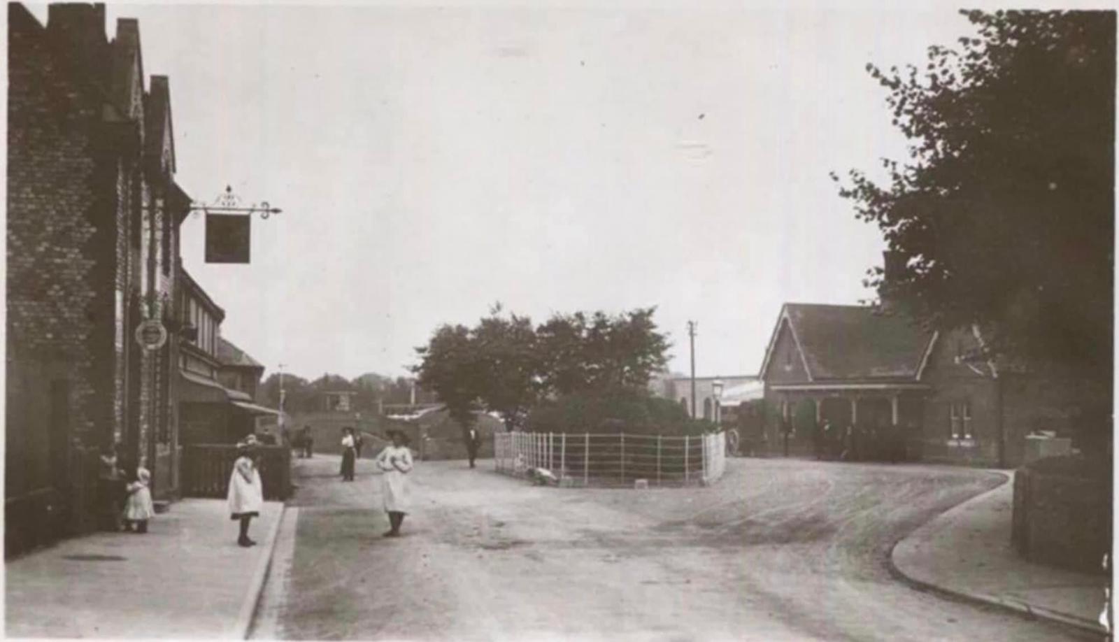 Vintage black and white photograph of a street scene with people and buildings.