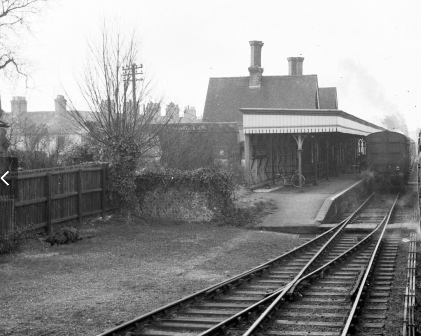 Vintage black and white photograph of a railway station with tracks and platform.