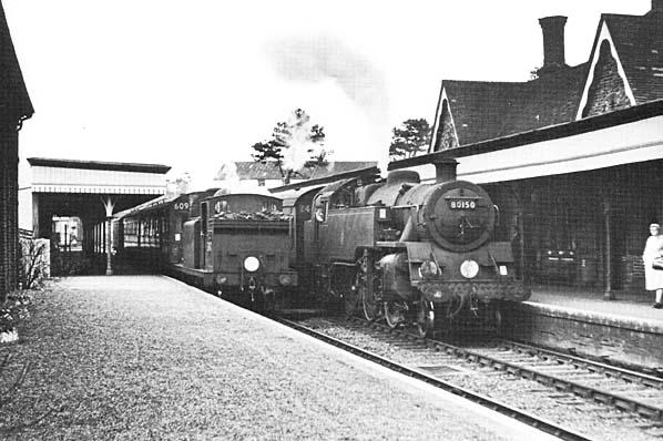 Vintage black and white photograph of a steam locomotive at a station platform.