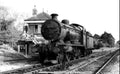 Vintage steam locomotive on railway tracks with a signal box in the background