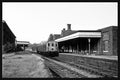 Vintage black and white photograph of a train station with a train on the tracks.