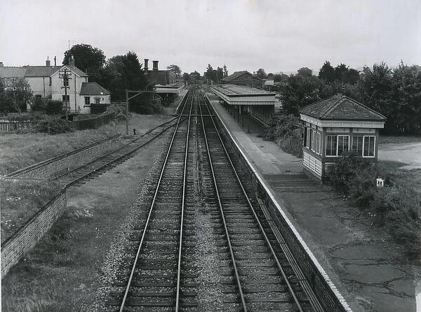 Vintage black and white photograph of a railway station with tracks, platform, and signal box.