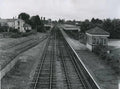 Vintage black and white photograph of a railway station with tracks and buildings.
