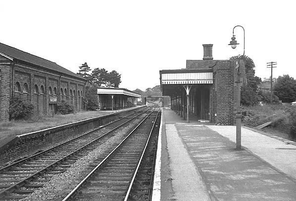 Vintage black and white photograph of a train station with tracks and platform.