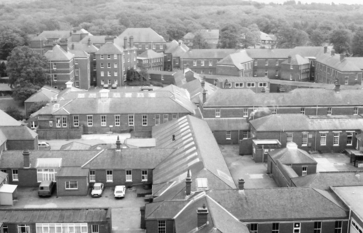 Aerial view of a large brick building complex surrounded by trees.