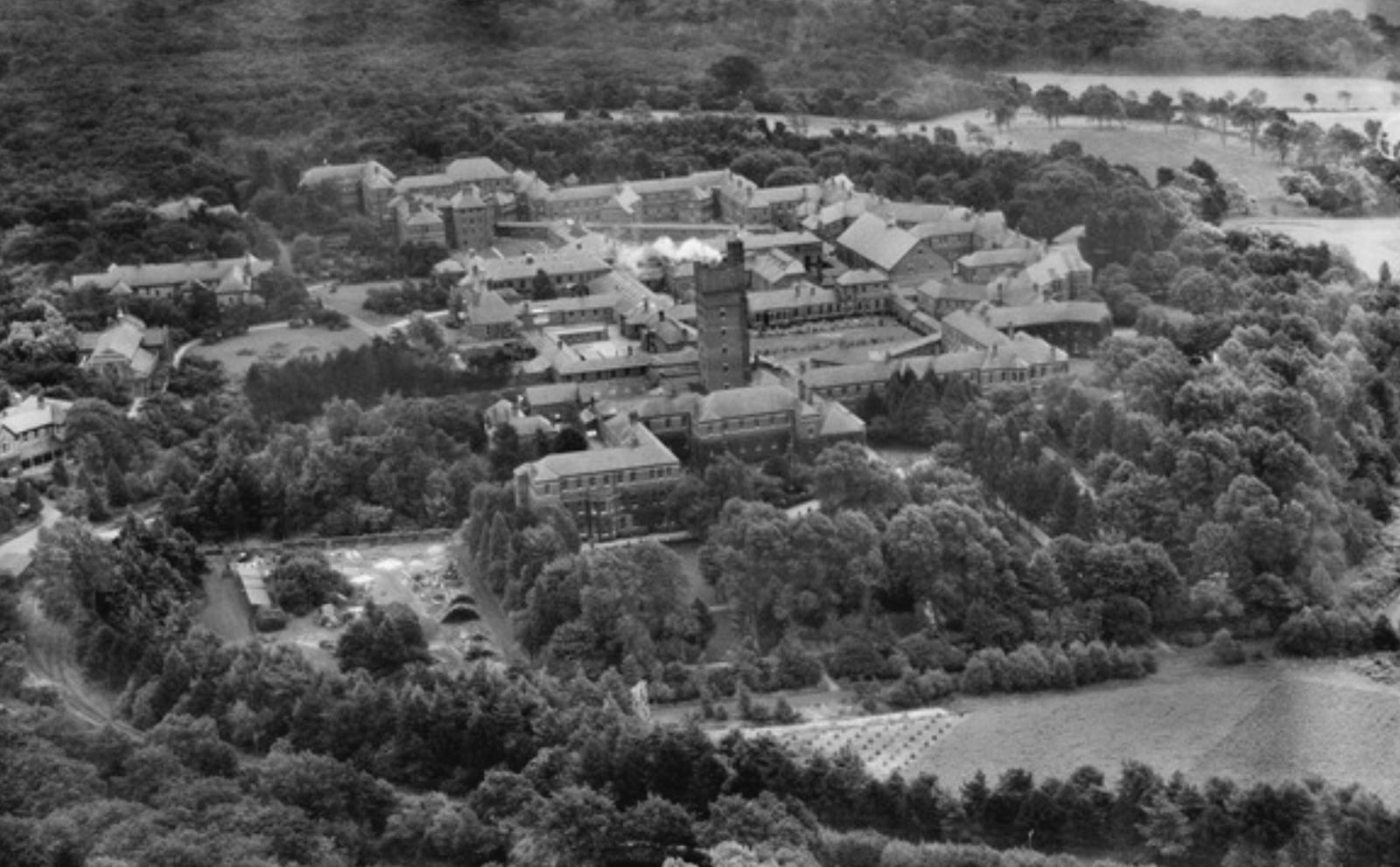 Aerial view of a large institutional building surrounded by trees