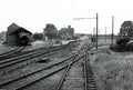 Black and white photograph of a railway yard with multiple tracks and buildings.