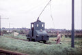 Small railway engine on tracks with a person nearby, set against a rural landscape.