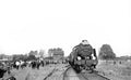 Vintage steam train on tracks with people around, black and white photo