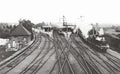 Vintage black and white photograph of a train station with a steam train on tracks.
