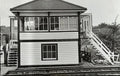 Black and white photograph of a two-story wooden signal tower on train tracks.