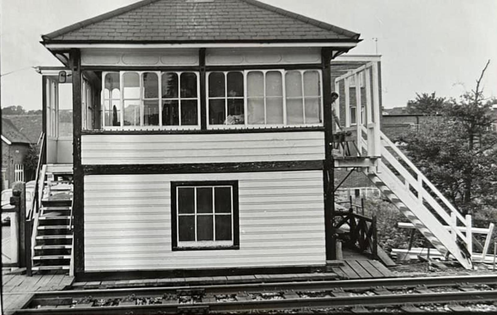 Black and white photograph of a two-story wooden signal tower on train tracks.