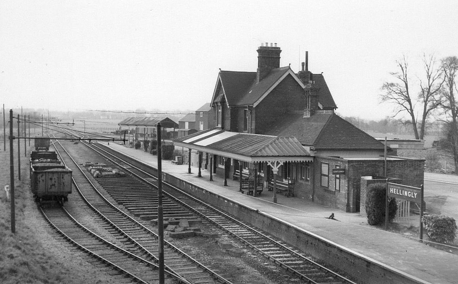 Vintage black and white photograph of a train station with a station building and tracks.