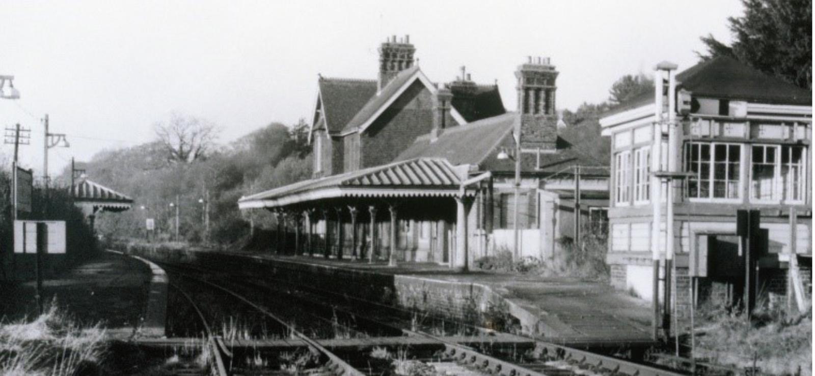 Vintage black and white photograph of a railway station with signal box and platform.