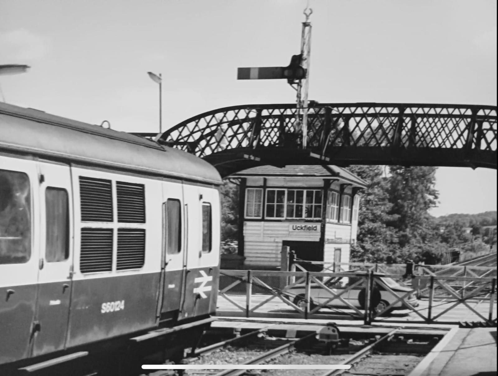 Vintage train at a railway crossing with a signal box and bridge in the background